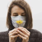 Woman with face mask looking at flower